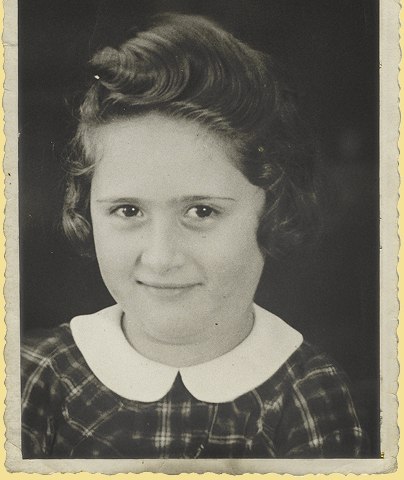 A black and white studio portrait of a young Rodi, likely from the mid-20th century. She has short, dark, wavy hair styled with a small curl pinned at the top. She is wearing a dark plaid dress with a white Peter Pan collar. She looks directly at the camera with a soft, slight smile and dark, expressive eyes. The background is a solid dark color.